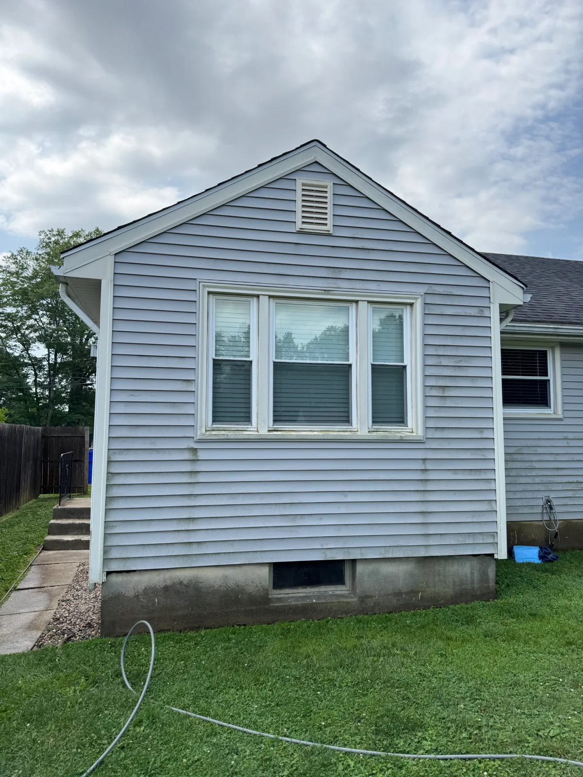 House siding before soft washing — green algae and grime
