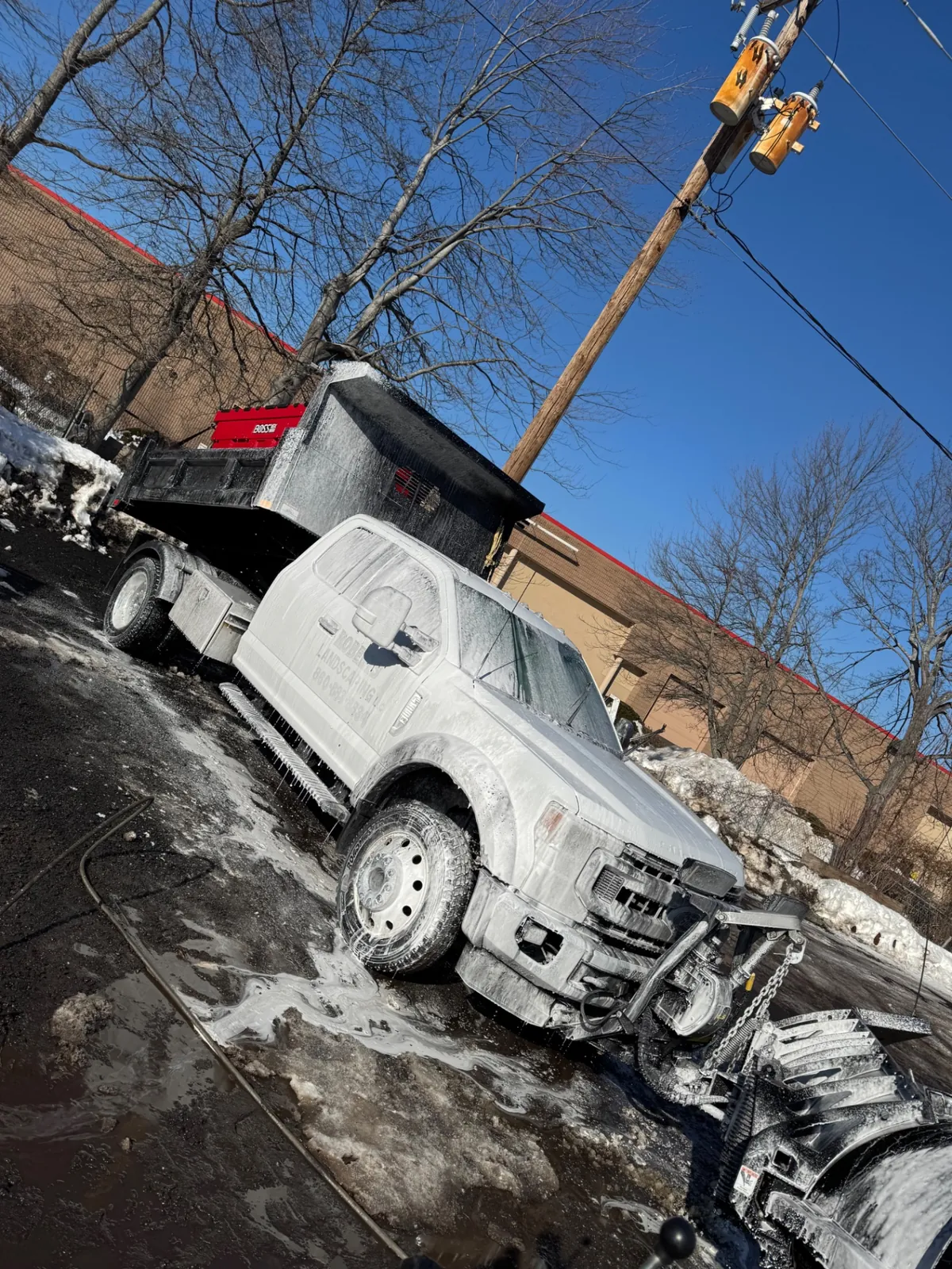 Work truck covered in cleaning foam during a winter hot wash