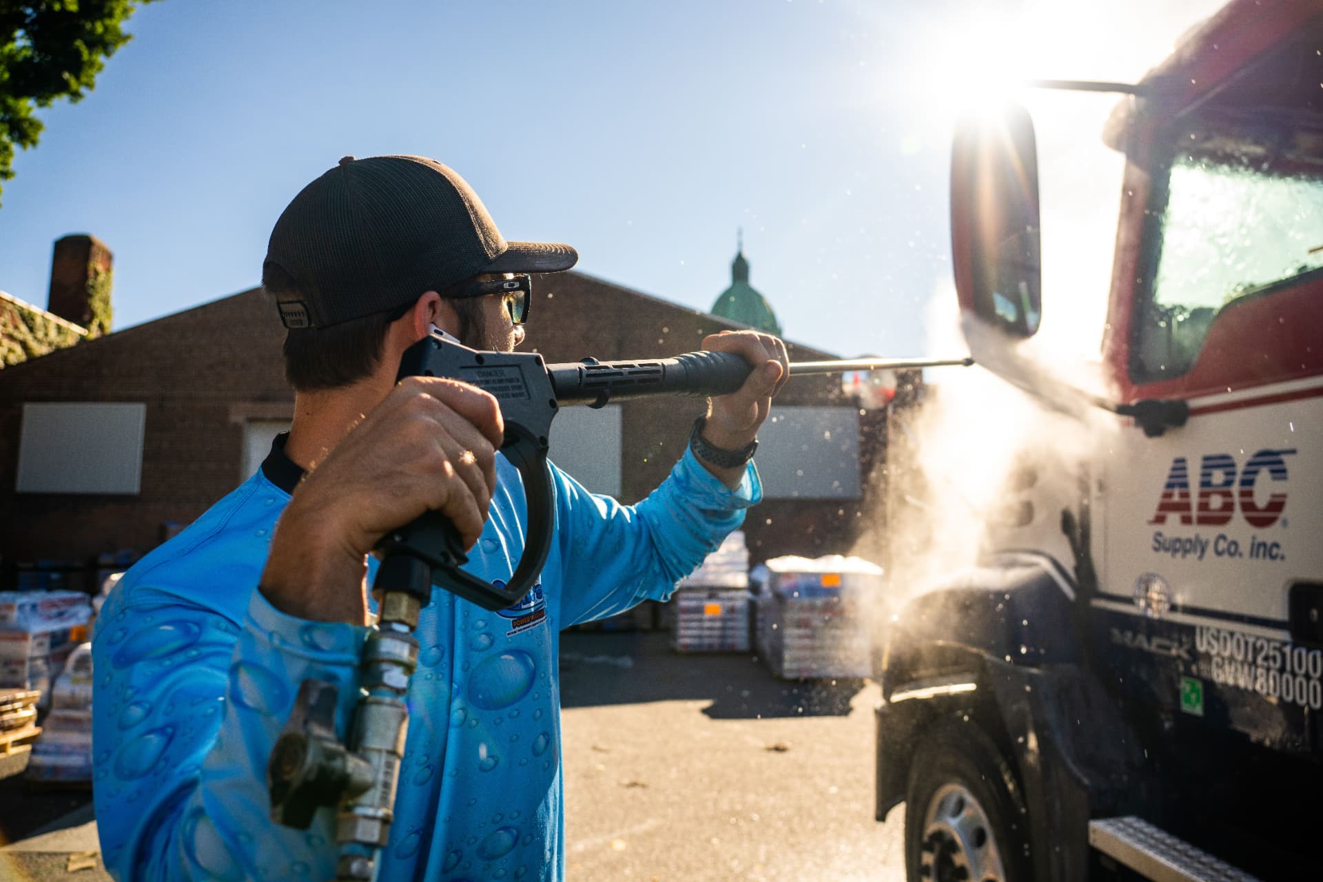 Technician applying cleaning solution to a commercial truck with a low-pressure wand