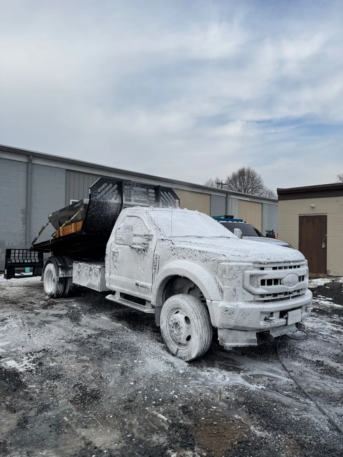 Commercial truck covered in hot-wash foam during winter fleet cleaning